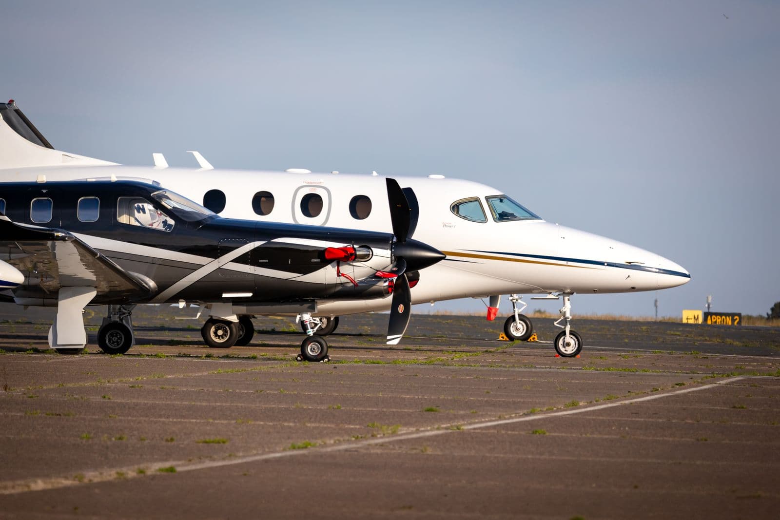Two private jets parked on an airport apron in soft morning light, wheels chocked awaiting departure — Private jet lifestyle club & charter experiences case study