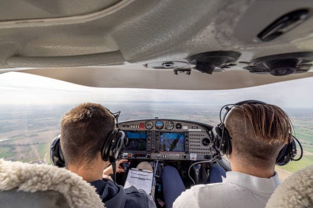 View from an aviation cockpit mid-flight with instruments illuminated