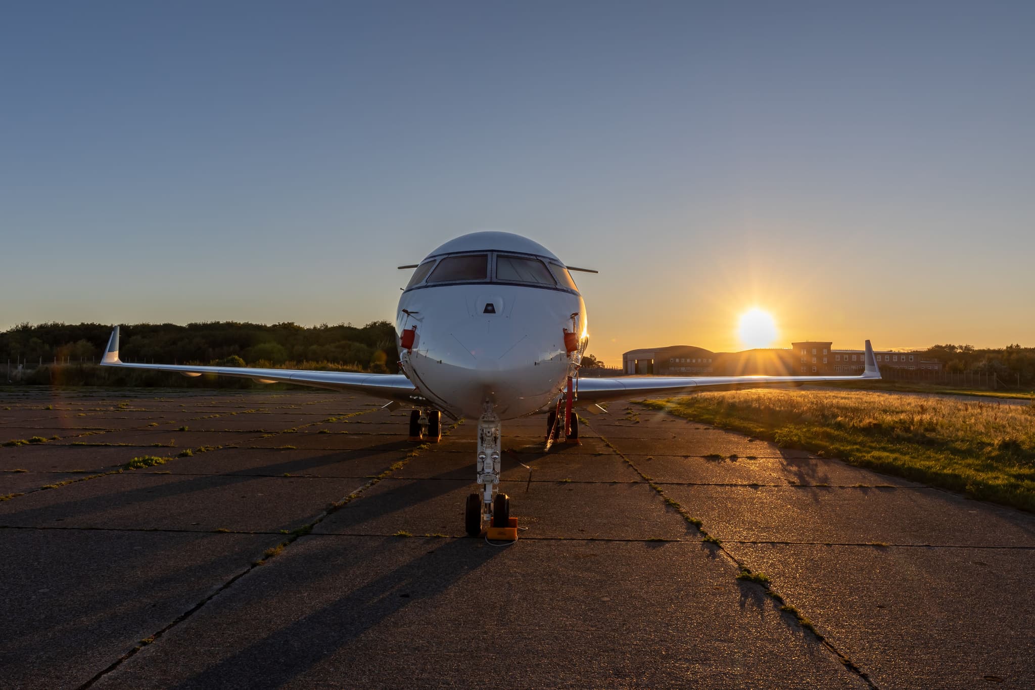 A private jet parked head-on on the runway at sunset
