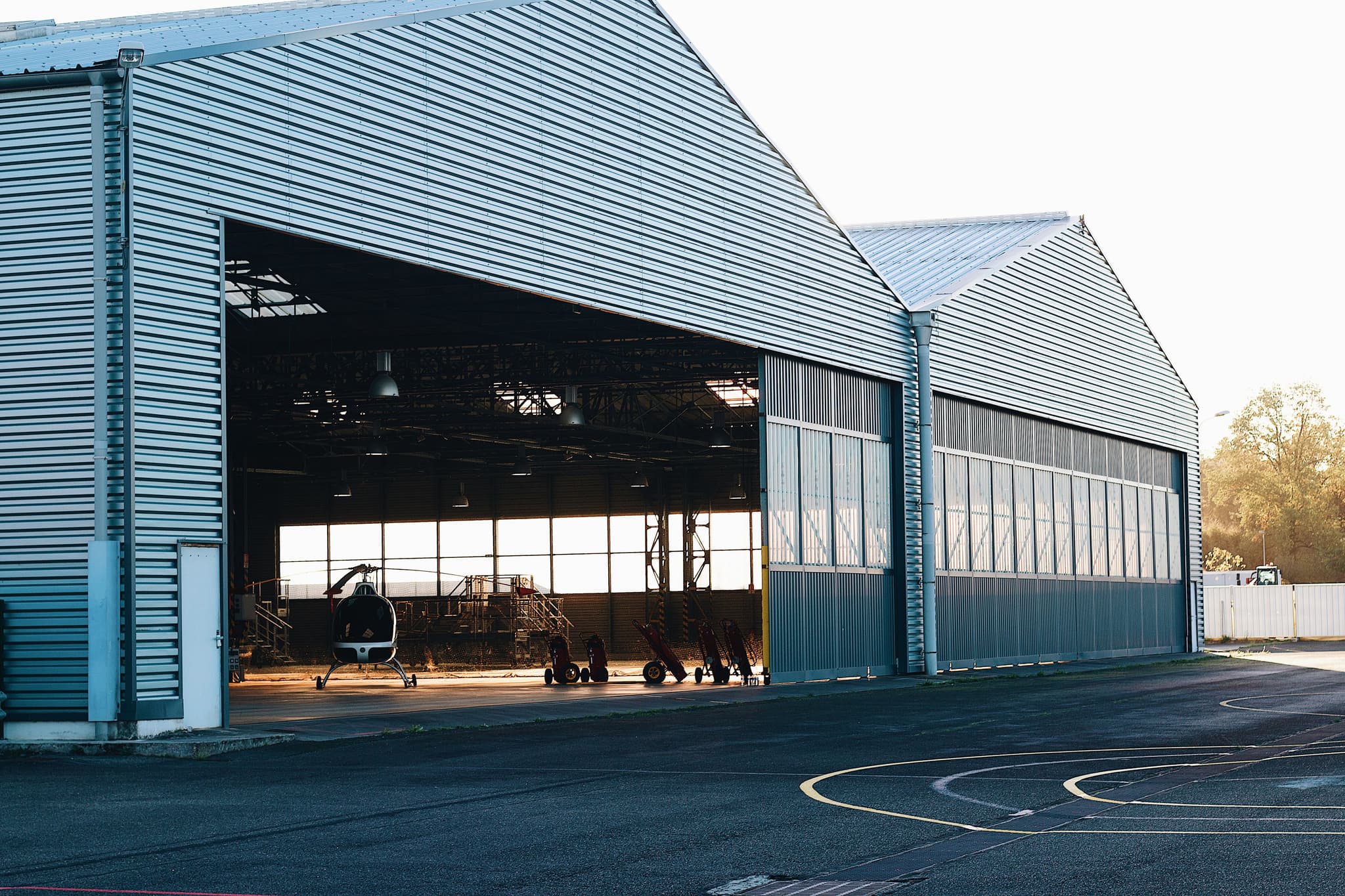 A large hangar at dusk with the door open onto an airfield apron