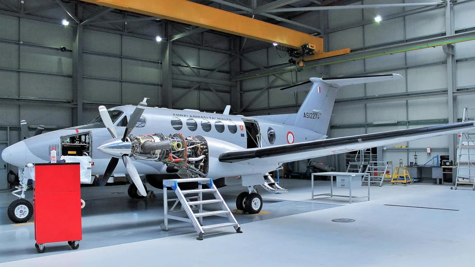 Business jet on jacks in a Part 145 hangar with technician working an engine inspection