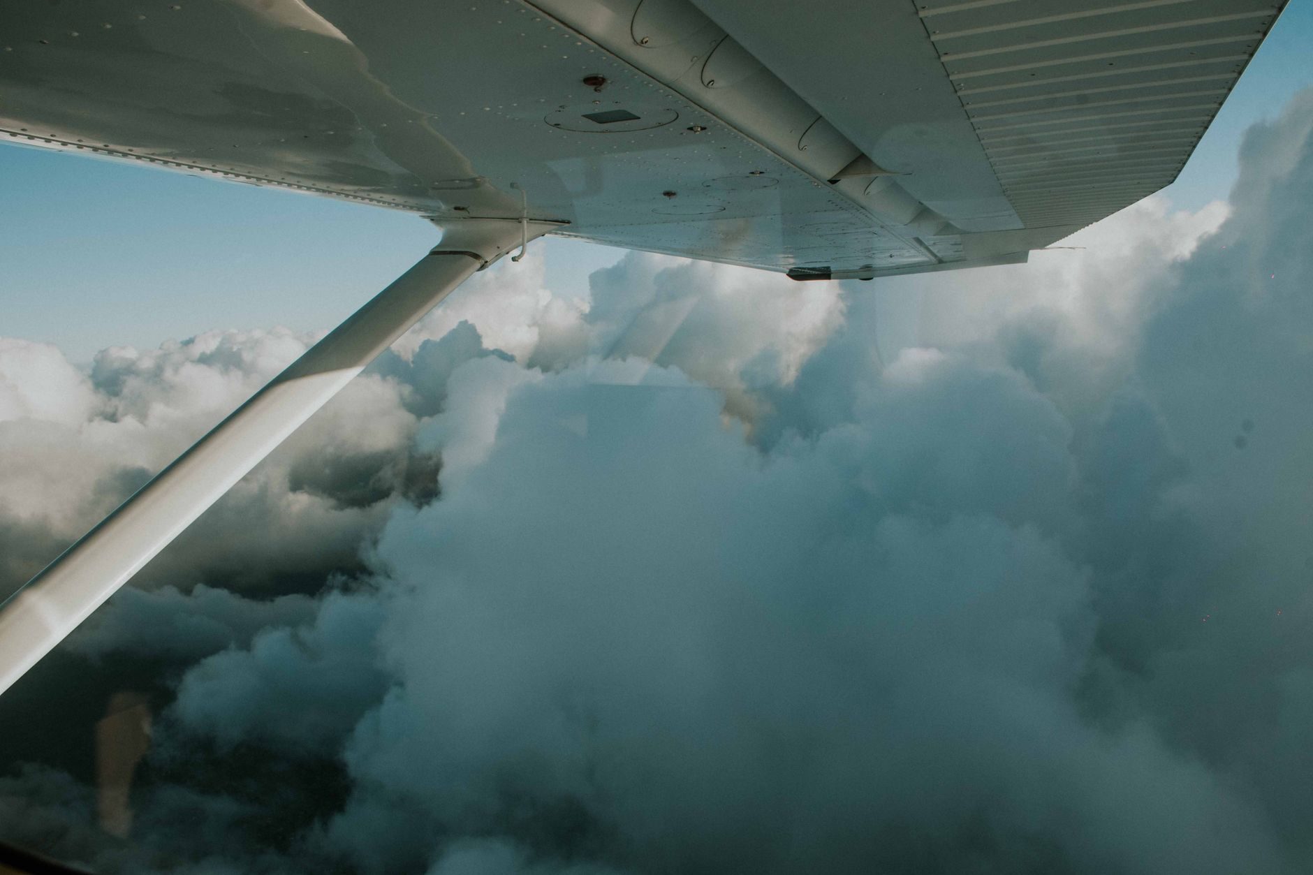Aircraft wing above a cloud layer seen from a cabin window