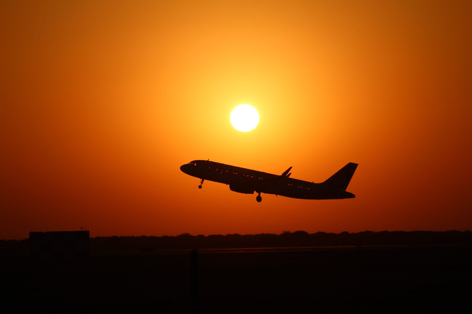 Silhouette of an airplane taking off against a vibrant sunset sky