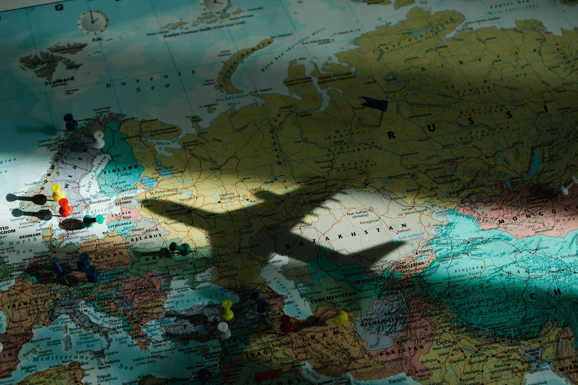 Airplane shadow cast across a map of Europe dotted with location pins, symbolising aviation research and planning