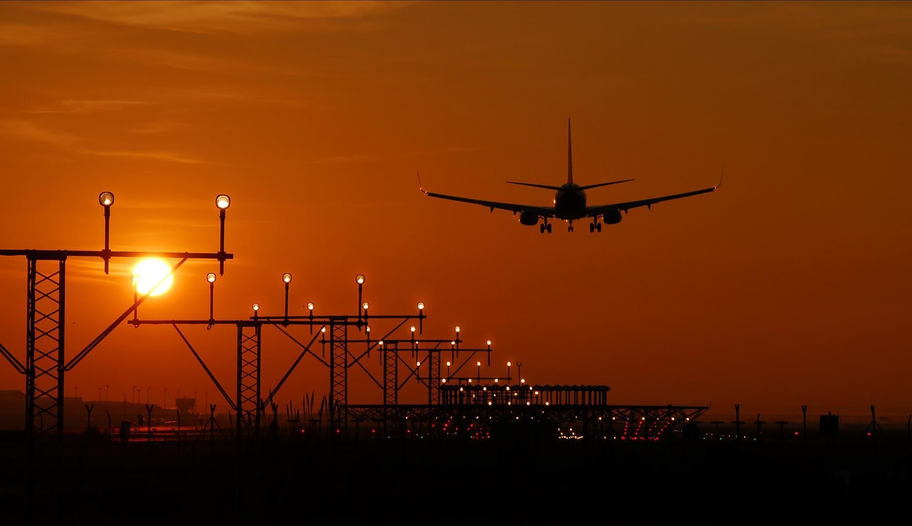 Aircraft on final approach above approach lights at sunset