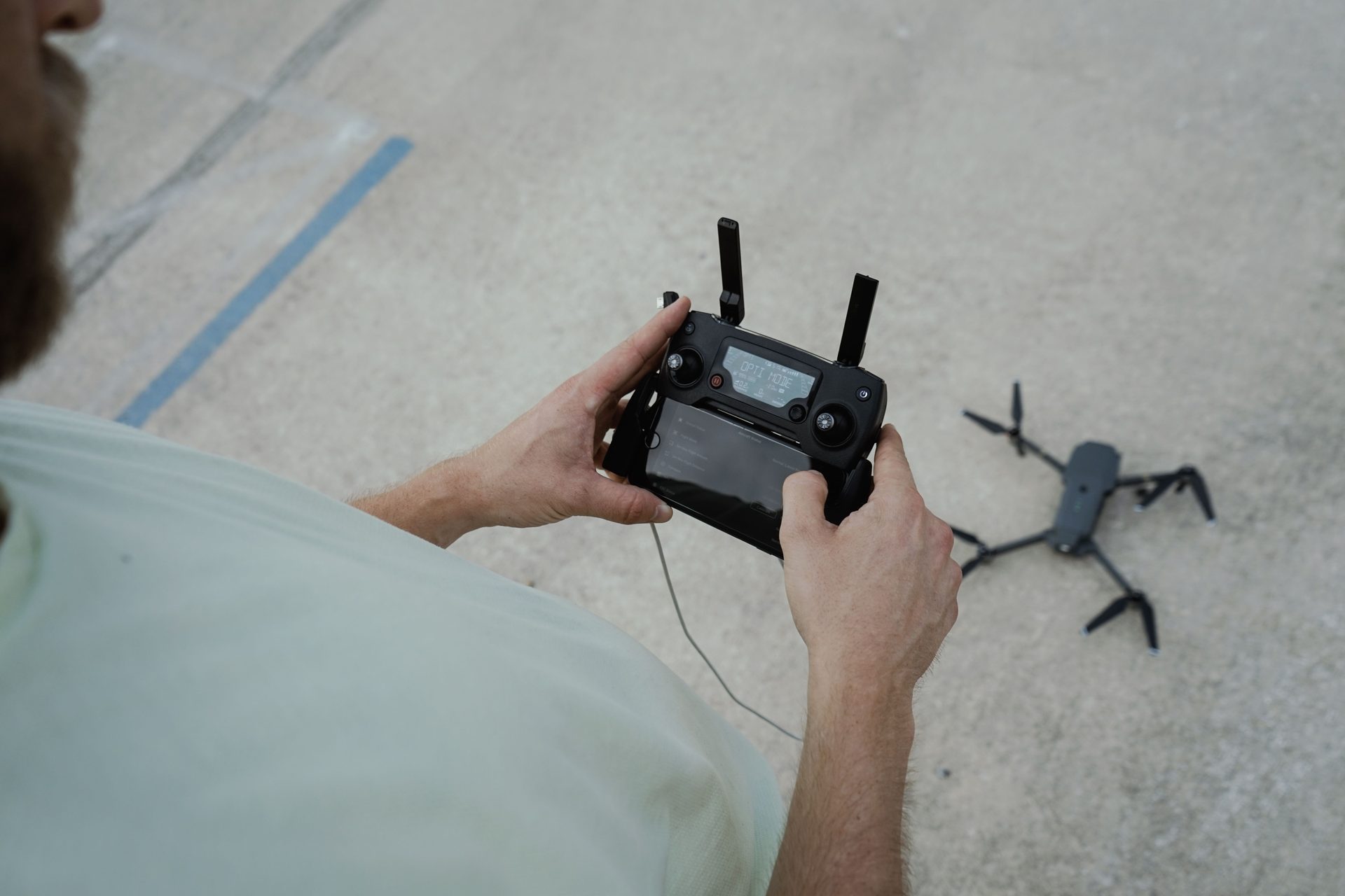 Drone operator preparing a quadcopter for flight on an outdoor surface