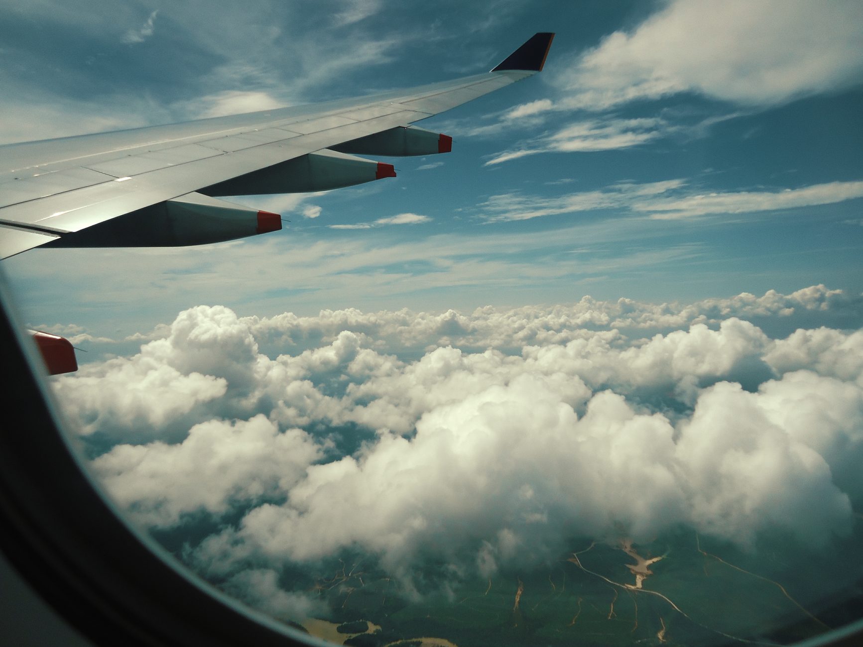 Charter aircraft wing cruising above a dense layer of cumulus clouds